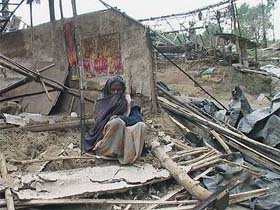 A woman sits in a demolished jhuggi in Hamirpur