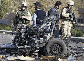 U.S. Army soldiers and Iraqi police examine the remains of a vehicle used by a suicide car bomber in central Baghdad