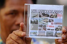 A Thai man, on Saturday, displays a video compact disc (VCD) with pictures and videos of the December 26 tsunami that hit Thailands tourist island of Phuket.