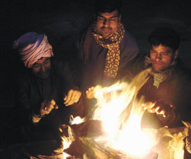 Daily wage earners huddle around a bonfire to ward off the cold in the Capital on Saturday. 