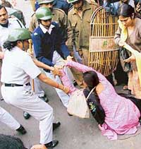 Women police personnel try to pull an SUCI activist during a demonstration staged to protest increasing transport fares in Kolkata on Monday. 