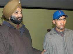 A police official stands beside a suspected Kashmiri rebel after he was arrested in Anantnag, about 60 km south of Srinagar, on Tuesday. The police said the rebel was going to disrupt the Republic Day celebrations. 