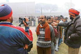 Men of the Punjab police use a video camera for recording particulars of migrant labourers at Mataur village