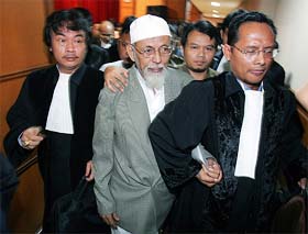 Indonesian cleric Abu Bakar Bashir walks with his lawyers out of his terrorism trial in Jakarta