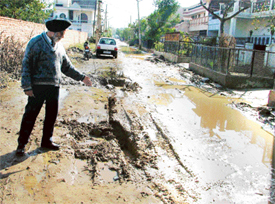 A resident shows the stretch of a dilapidated road in Dugri, Phase I
