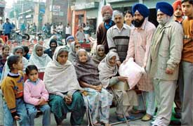 A member of the Manna Singh Manufacturers Association gives free ration to a needy woman in Ludhiana