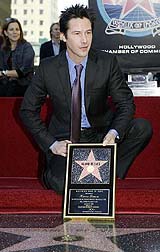 Keanu Reeves displays a plaque over the star he received during a ceremony