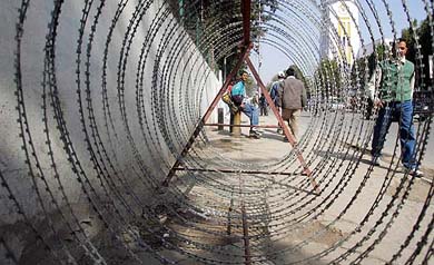 A man sits next to barbed wires in a street at Kathmandu