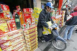 A deliveryman leaves his shop on motor cycle loaded with boxes of soft drinks in downtown Hanoi on Friday.