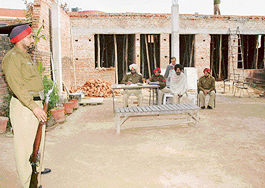 An accused sits with policemen out in the open at Mullanpur Garibdass police station on Monday.