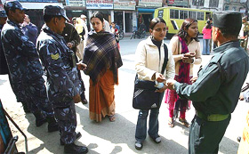 Women enter a college after getting their identity cards checked by Nepalese policemen and security guards in Kathmandu on Monday
