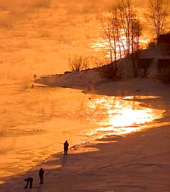 Fishermen stand on the icy bank of the Yenisei river in the Siberian city of Krasnoyarsk on Sunday