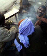 Nepalese labourers drink tea on a pavement
