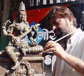 An artist gives final touches to an idol of Goddess Saraswati
