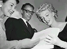 Arthur Miller looks on as Marilyn Monroe signs an autograph on May 21, 1958