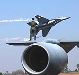 A US defence personnel stands on the wing of a KC-135 tanker aircraft, while a Russian SU-30 takes off during the last day of the fifth edition of the Aero India-2005 at Yelhanka Air Base, near Bangalore, on Sunday.