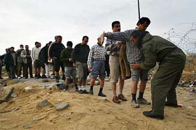 Palestinian workers line up to get checked by a security officer before entering the Israeli controlled industrial zone between Israel and the Gaza Strip