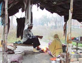This elderly couple sits near a fire to ward off cold in Ludhiana, on Tuesday