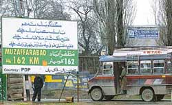A passenger bus passes a hoarding showing the distance to Muzaffarabad in Parimpora on the outskirts of Srinagar on Wednesday. 