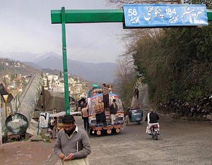  Pakistani passenger bus passes under a roadsign "Srinagar of India 184km", near a model of a missile, aiming towards India, in PoK's capital Muzaffarabad