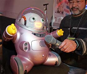 Yasushi Hattori, a designer of Business Design Laboratory Co. Ltd., holds a microphone for his companys robot, Ifbot