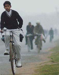 A student cycles with a hand in his pocket to ward off the chill as cold conditions return to the city