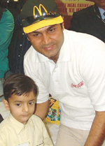 Star batsman Virender Sehwag with one of the lucky winners of the Happy Meal contest organised by McDonald's in the Capital on Sunday