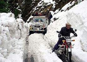 A resident rides a motorbike on a snow-covered road in Neelum Valley, about 77 km north-east of Muzaffarabad, the capital of Pakistan occupied Kashmir on Tuesday. 