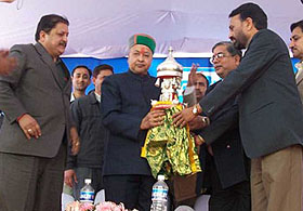 Executive Director of Kol Dam Hydro Project K.B. Dubey presents an idol of hill God to Chief Minister Virbhadra Singh at a public meeting in Chameon in Bilaspur district on Saturday.