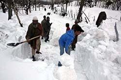 Kashmiri villagers remove snow from a street in Shopian, 55 km south of Srinagar, on Saturday. 