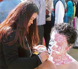 A participant paints the face of a student during "Ehsaas-2005" at the PCTE in Ludhiana