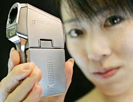 A campaign girl for Japans Sanyo Electric Co. shows off the companys new digital still and movie camera, Xacti series, DMX-C5, at its Tokyo office on Tuesday. 