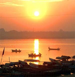 Fishermen paddle their boats as sun rises over the Ganges river