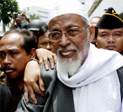 Indonesian Muslim cleric Abu Bakar Bashir is ushered out of a makeshift courtroom in Jakarta