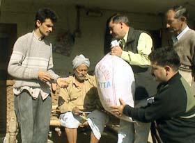 HP Sarv Kalyankari Society president Rajendra Rana gives cash and relief to a fire victim of Hamirpur at Dodroo village