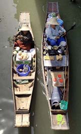 Two boats, one selling coconuts and another Thai pancakes, row at the floating market in Ratchaburi province on Saturday night. 
