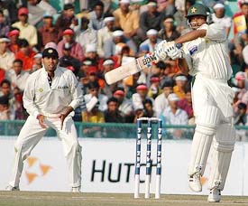 Asim Kamal of Pakistan hits a shot as V.V.S. Laxman looks on during the first days play of the first Test in Mohali on Tuesday.