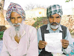 Fakir Singh shows the recovery notice he received from the Social Security Department at Ghalib Kalan village in Ludhiana. Amar Singh is also seen in the picture. 