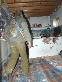 A security officer searches a house where a foreign mercenary was killed in an encounter in Pampore