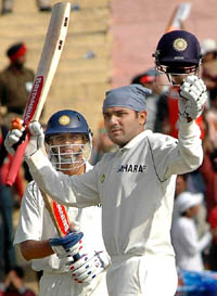 Virender Sehwag acknowledges the crowd after scoring 150 runs as Rahul Dravid looks on during the third days play of the first Test in Mohali 