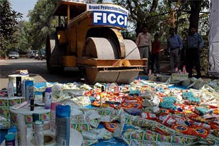 A bulldozer destroys a pile of counterfeit products on World Consumer Rights Day in New Delhi on Tuesday. 