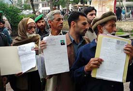 Kashmiri men stand in a queue on Friday and show travel permit applications before submitting the forms required to ride a bus from Muzaffarabad, the capital of Pakistan-Occupied Kashmir, to Srinagar. 