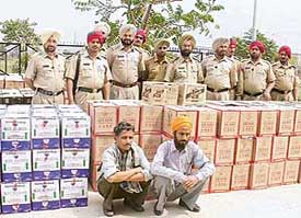 Police personnel with the accused and boxes of liquor seized from them in Sohana