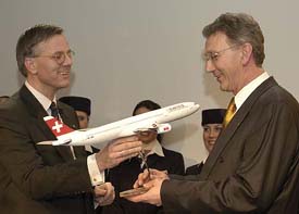 Swiss International Air Lines CEO Christoph Franz (L) hands out the model of a Swiss passenger airplane to Wolfgang Mayrhuber, CEO of German airline Lufthansa, during a press conference to announce the merger of the two companies on Tuesday in Zurich. 
