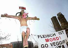 German artist Benjamin Schmidt is tied on a wooden cross next to a placard with the slogan flesh is murder, go veggie during a demonstration of People for the Ethical Treatment of Animals in Berlin