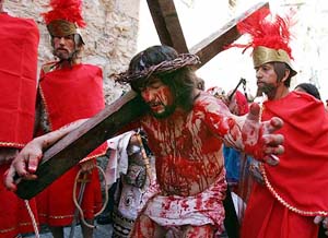 A pilgrim playing the part of Jesus Christ, complete with a crown of thorns and actors blood, carries a cross along the Via Dolorosa towards the Church of the Holy Sepulchre during the Good Friday procession in Jerusalems Old City on Friday.