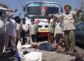Members of the Punjab Roadways Action Committee lie before a private bus without any route permit in Amritsar on Wednesday. 