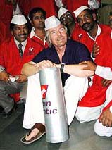 Chairman of Virgin Atlantic Richard Branson wearing a traditional cap and a pajama which is the normal dress code of a Mumbai dabbawallah poses for a photograph with them at Churchgate Station in Mumbai on Friday.