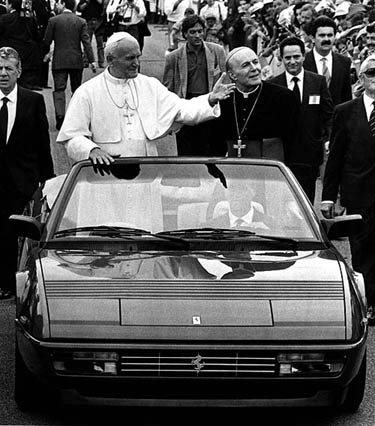 Pope John Paul II (2nd L) waves to the crowd from a Ferrari Mondial during a visit of Pontiff to Maranello car's factory in Rome on June 4, 1988