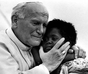 Pope John Paul II hugs three-year-old Monik and her one-year-old sister Zin, whose eye can be seen between the Pope's chest and hand in Antananarivo on April 29, 1989.